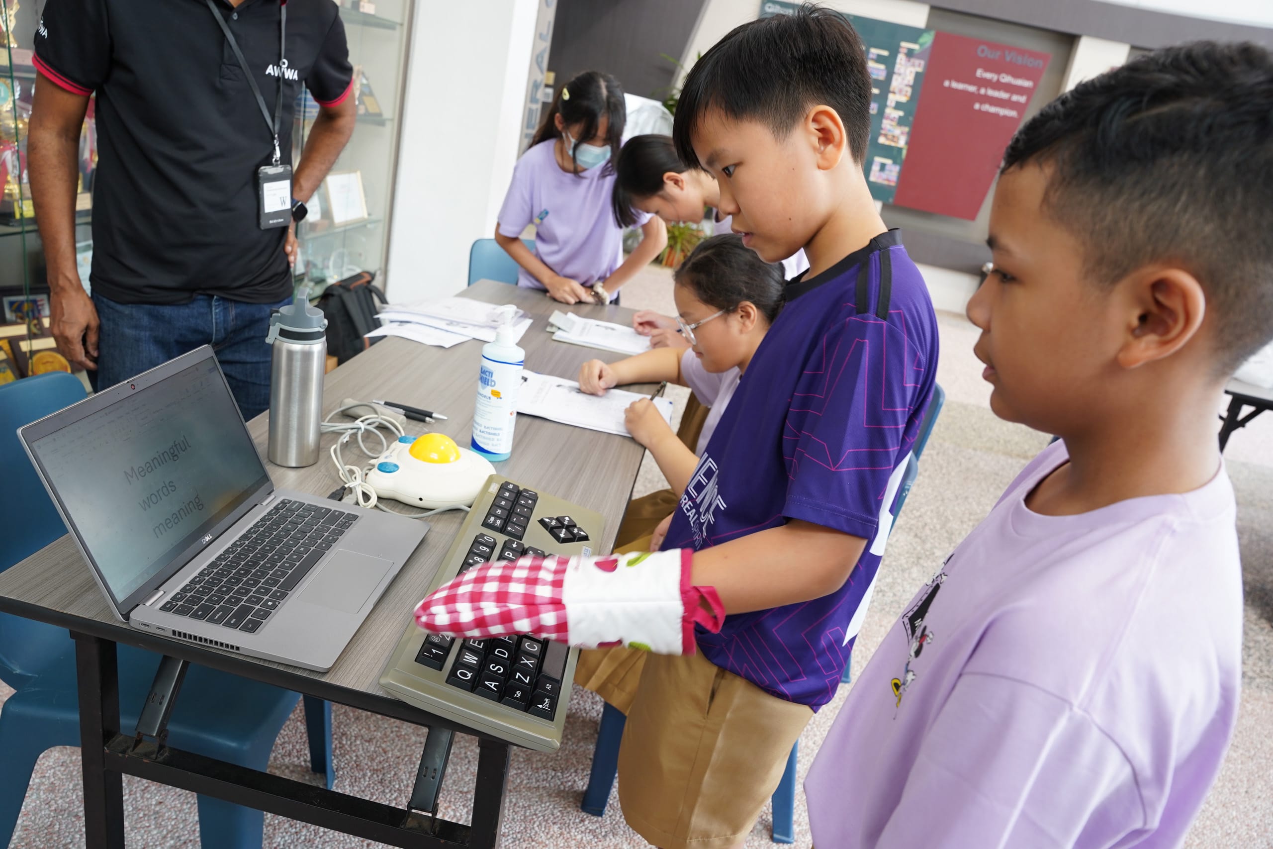 Student wearing mitten while pressing a large keyboard